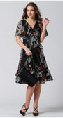 Woman wearing a flowing boho short dress with flounces and a deep V-neckline, holding a black handbag and wearing heels