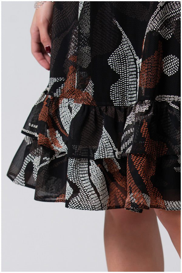 Close-up of Short Dress Lola hem showing black fabric with white and rust geometric patterns and soft flounces.