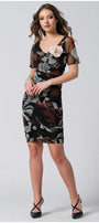 Woman wearing fitted dress with sheer short sleeves and removable flower brooch, posing confidently