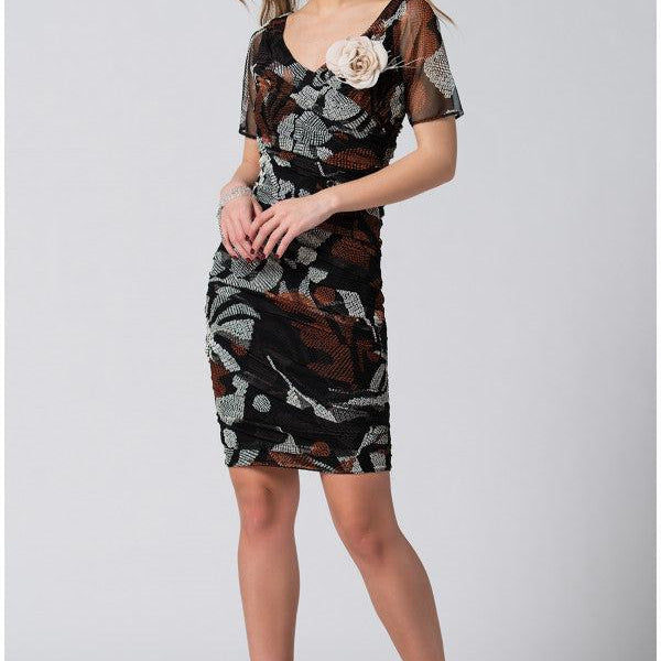 Woman wearing fitted dress with sheer short sleeves and removable flower brooch, posing confidently