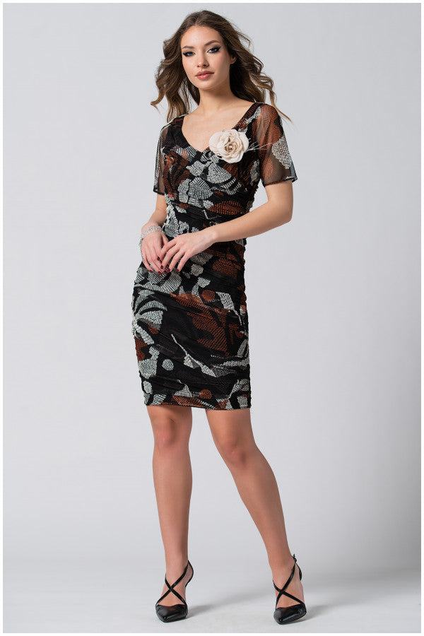 Woman wearing fitted dress with sheer short sleeves and removable flower brooch, posing confidently
