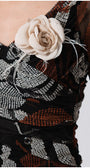 Close-up of SHORT DRESS LOLA with sheer sleeves and removable cream flower brooch on patterned fabric bodice
