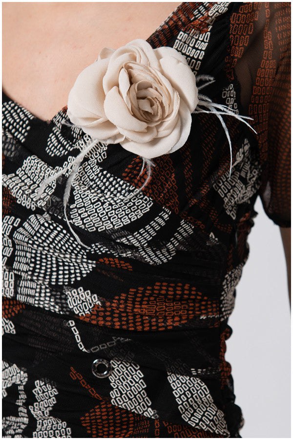 Close-up of SHORT DRESS LOLA with sheer sleeves and removable cream flower brooch on patterned fabric bodice