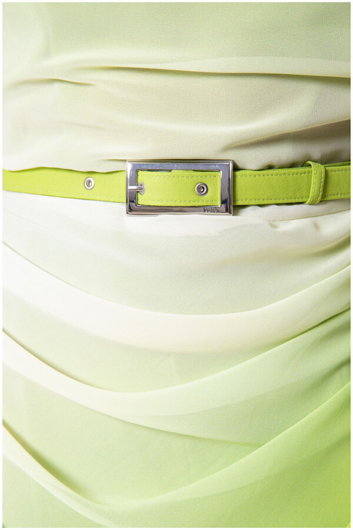 Close-up of a light green dress with a belt featuring a metallic buckle.