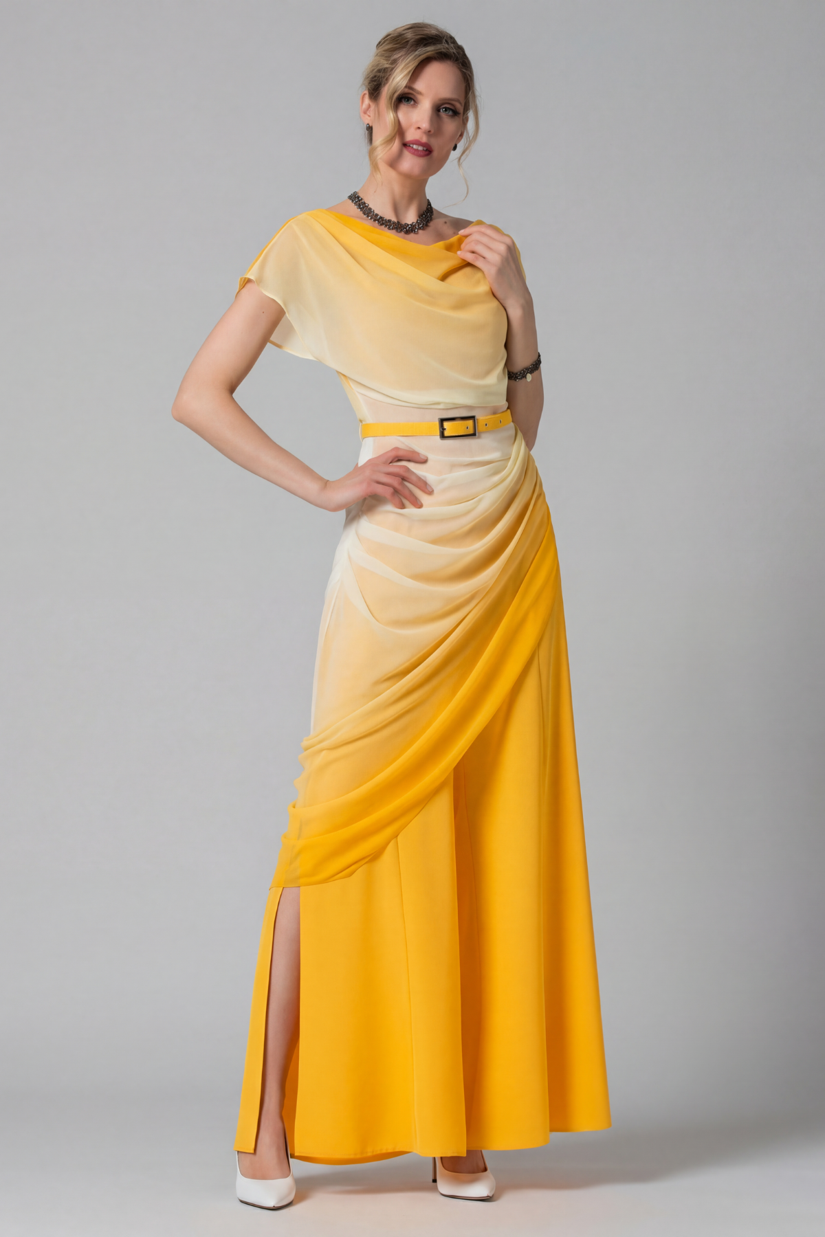 Woman wearing a yellow and beige dress with a belt on a gray background