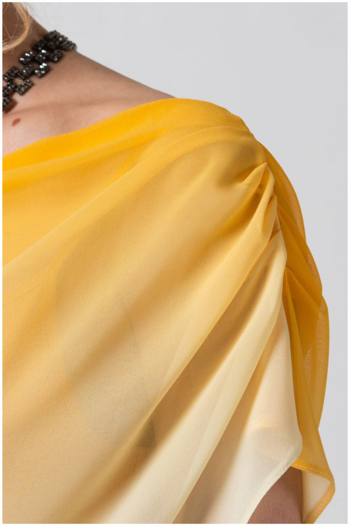 Yellow saree draped over a shoulder with a plain background