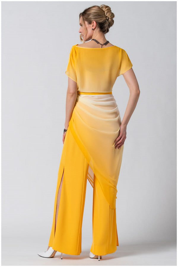Woman wearing luminous ombre yellow Overall Tina with flowing layered fabric and belted waist, back view.