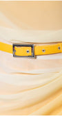Close-up Yellow Overall detail of luminous yellow ombre belt with silver buckle accentuating waist on flowing fabric overall dress.