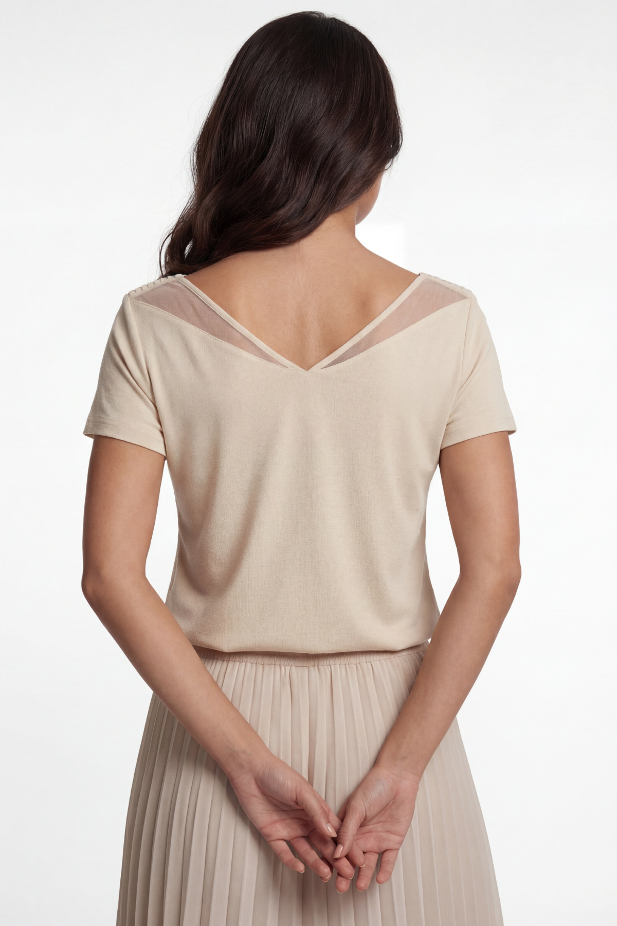 Woman wearing a beige top and skirt set on a white background