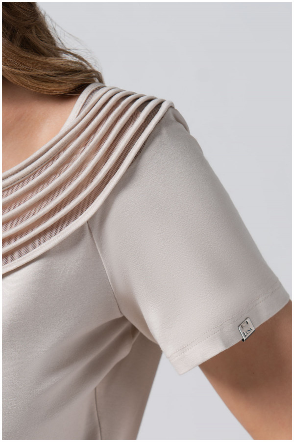 Beige short-sleeve top with a subtle pattern on a plain background