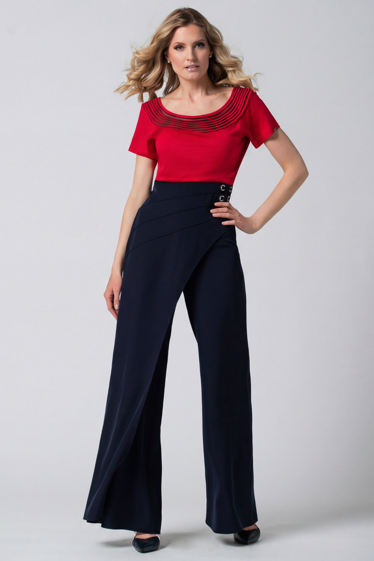 Woman wearing a red top and navy pants on a white background