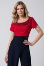 Woman wearing a red top and navy pants on a gray background