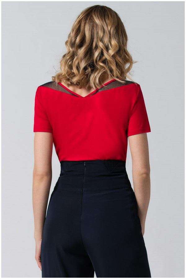 Woman wearing a red office elegant blouse Lola Top with pleated neckline detail, paired with high-waisted black trousers, back view.