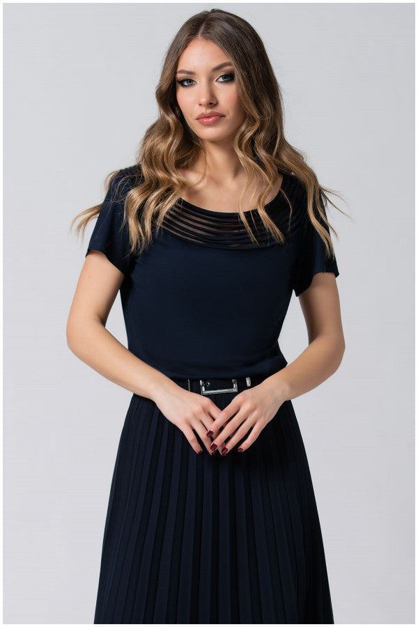 Woman wearing navy Lola business Top with pleated neckline and short sleeves paired with a pleated skirt