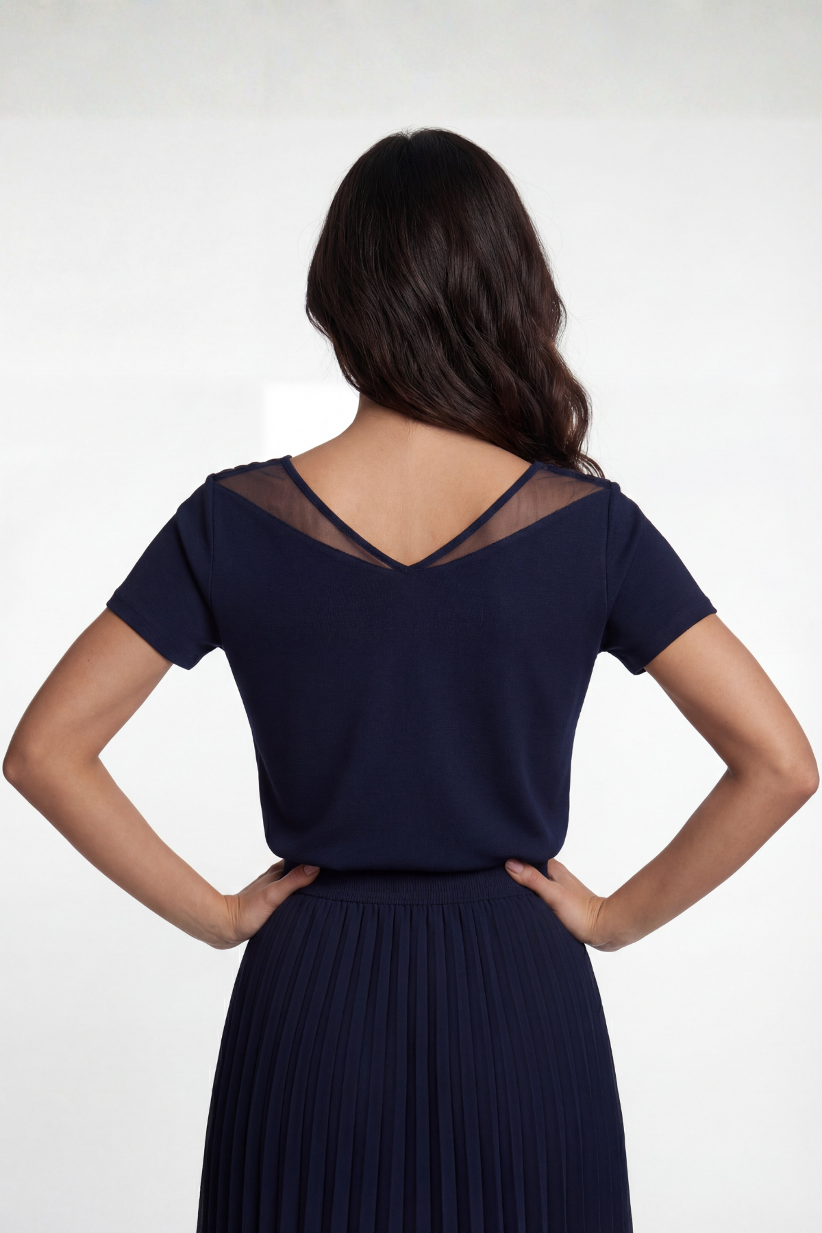 Woman wearing a navy blue dress with sheer back panels on a white background