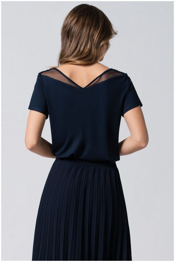 Back view of navy Lola business Top with short sleeves and sheer V-neck detail paired with a pleated skirt