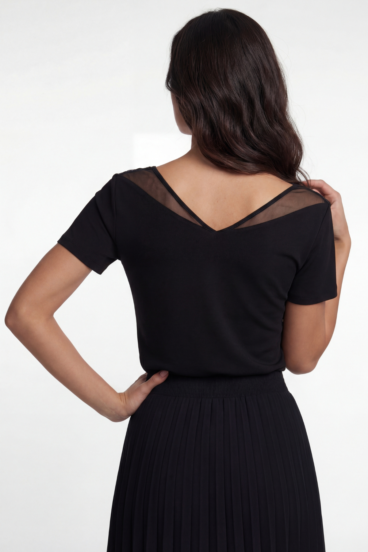 Woman wearing a black dress with sheer sleeves on a white background