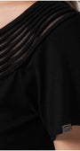 Close-up of black Lola business Top featuring a pleated neckline and short sleeve with a small brand tag.