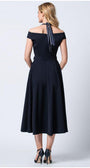 Woman wearing navy off-shoulder elegant midi dress with halter tie and high heels, standing against white background