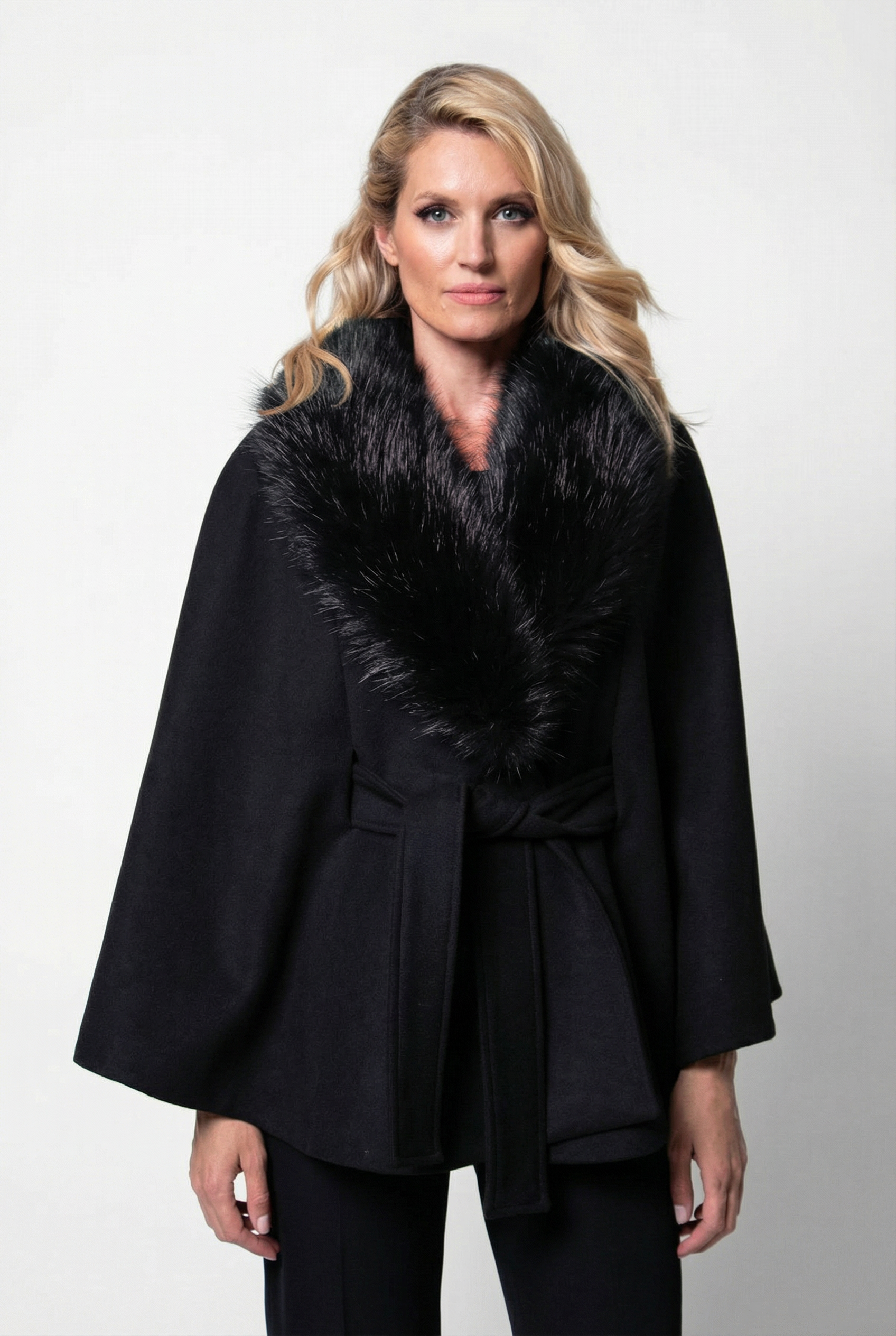 Woman wearing a black coat with a fur collar against a white background