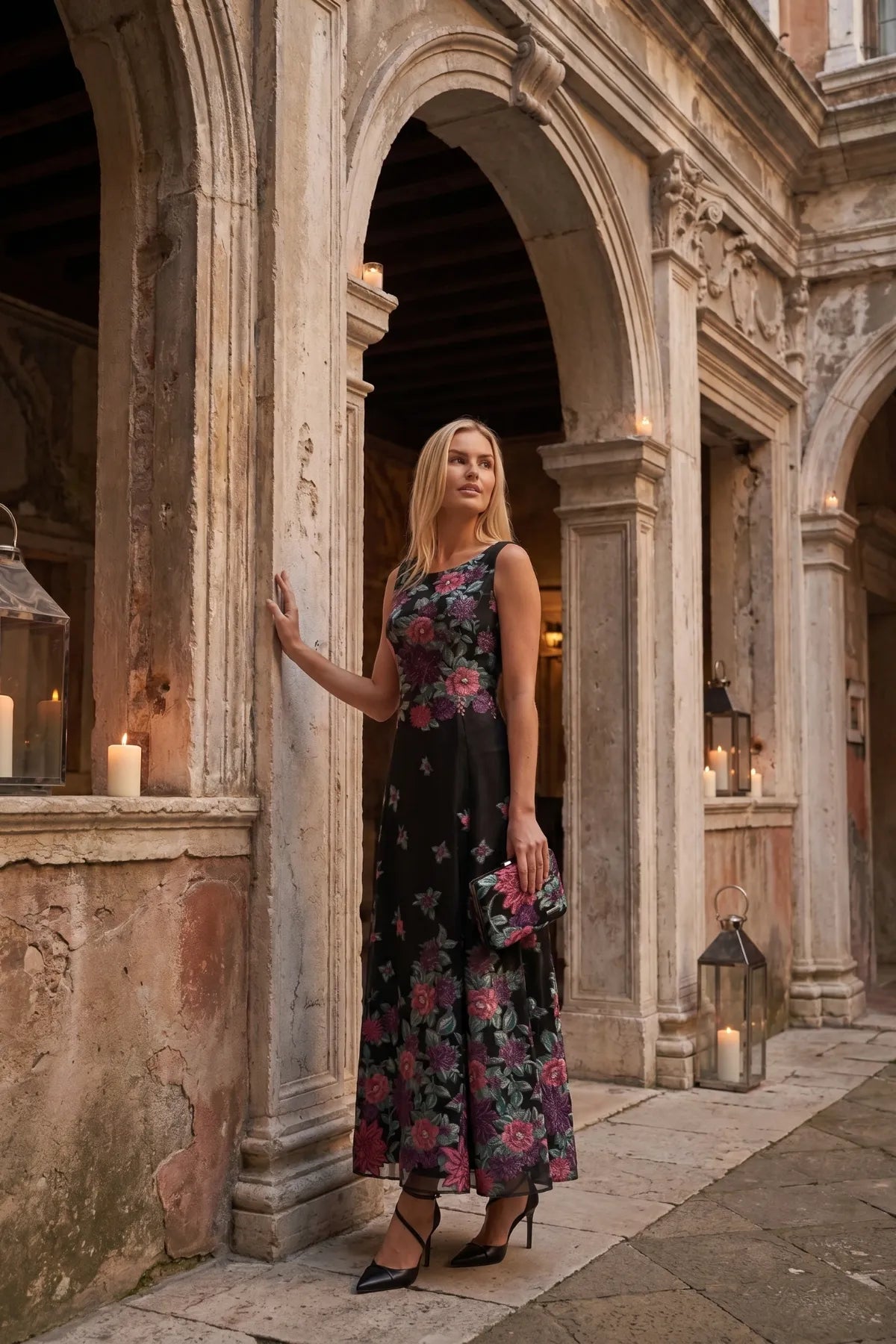 Regina floral clutch styled with a matching black floral dress in a historic courtyard.