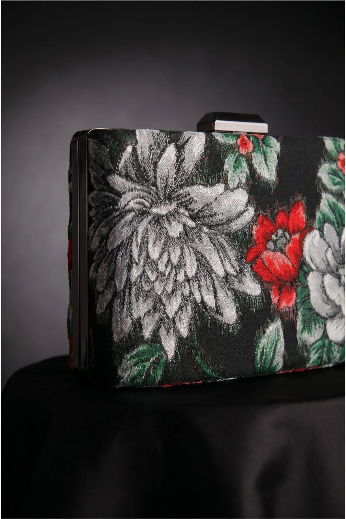 Close-up of Regina floral clutch showing the woven floral textile, top clasp, and textured finish.
