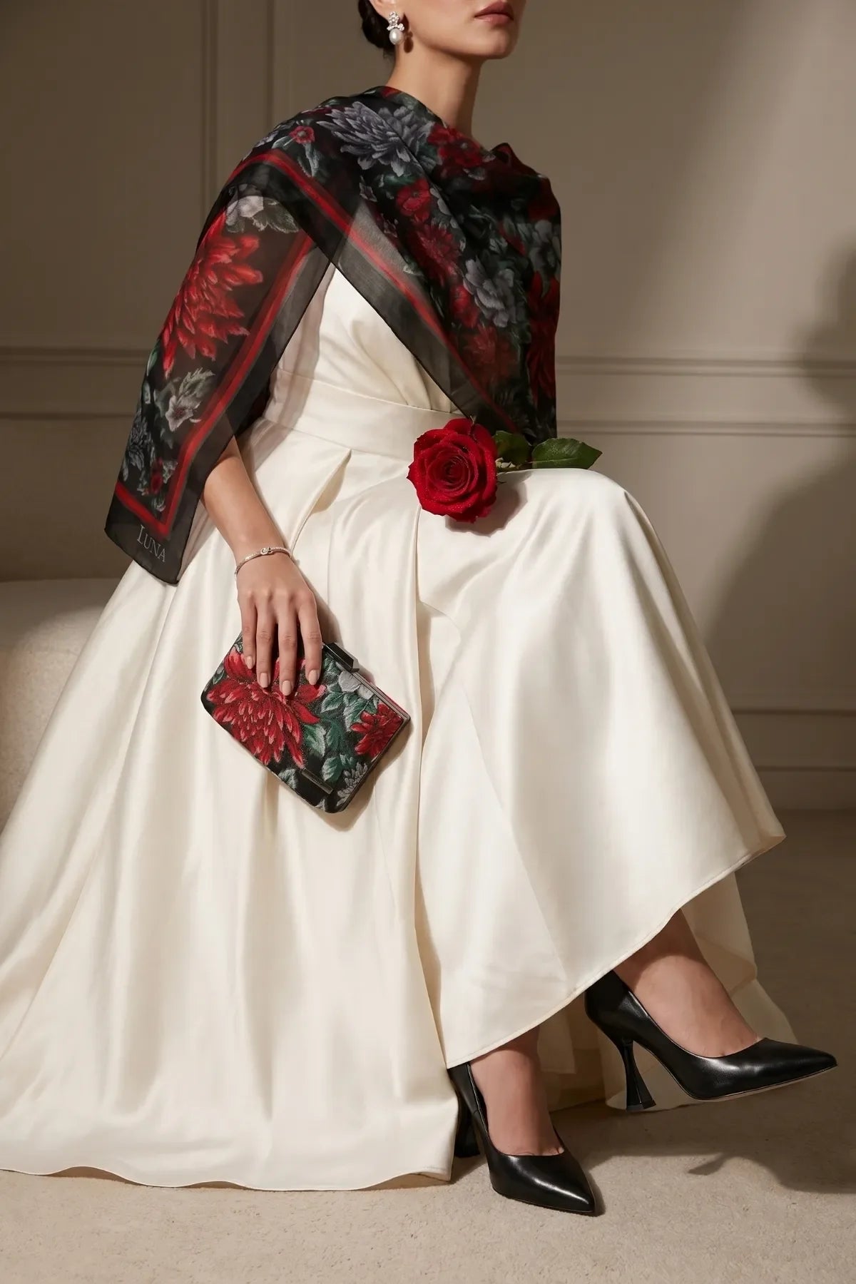 Regina floral clutch held with an ivory dress and black floral scarf for polished formal styling.