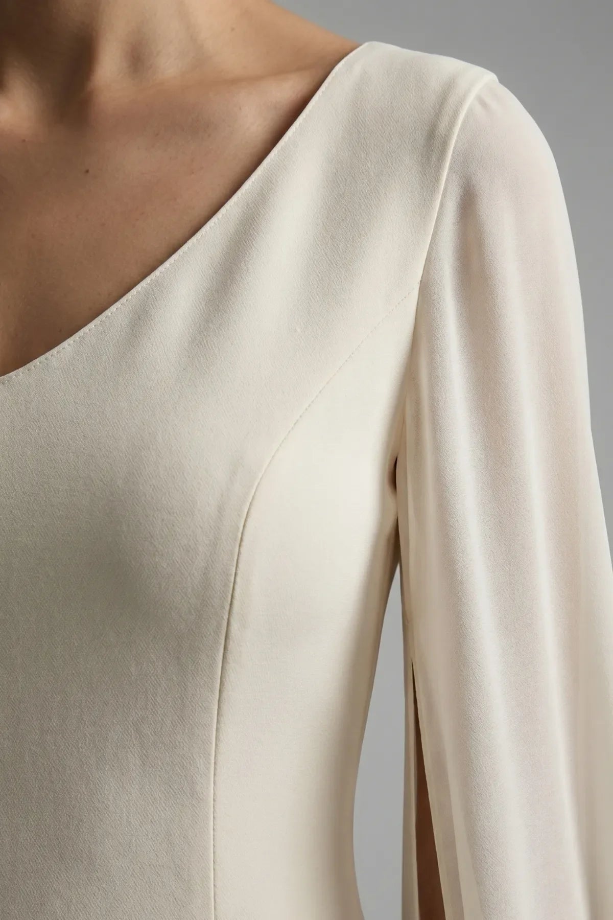 Rebeka ivory short dress shown flat with V neckline, waist charm and knee-length sheath line