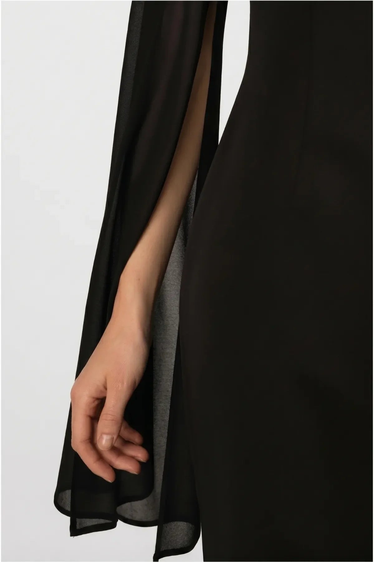 Detail of the Rebeka sheer chiffon cape sleeve, open along the arm over the black sheath