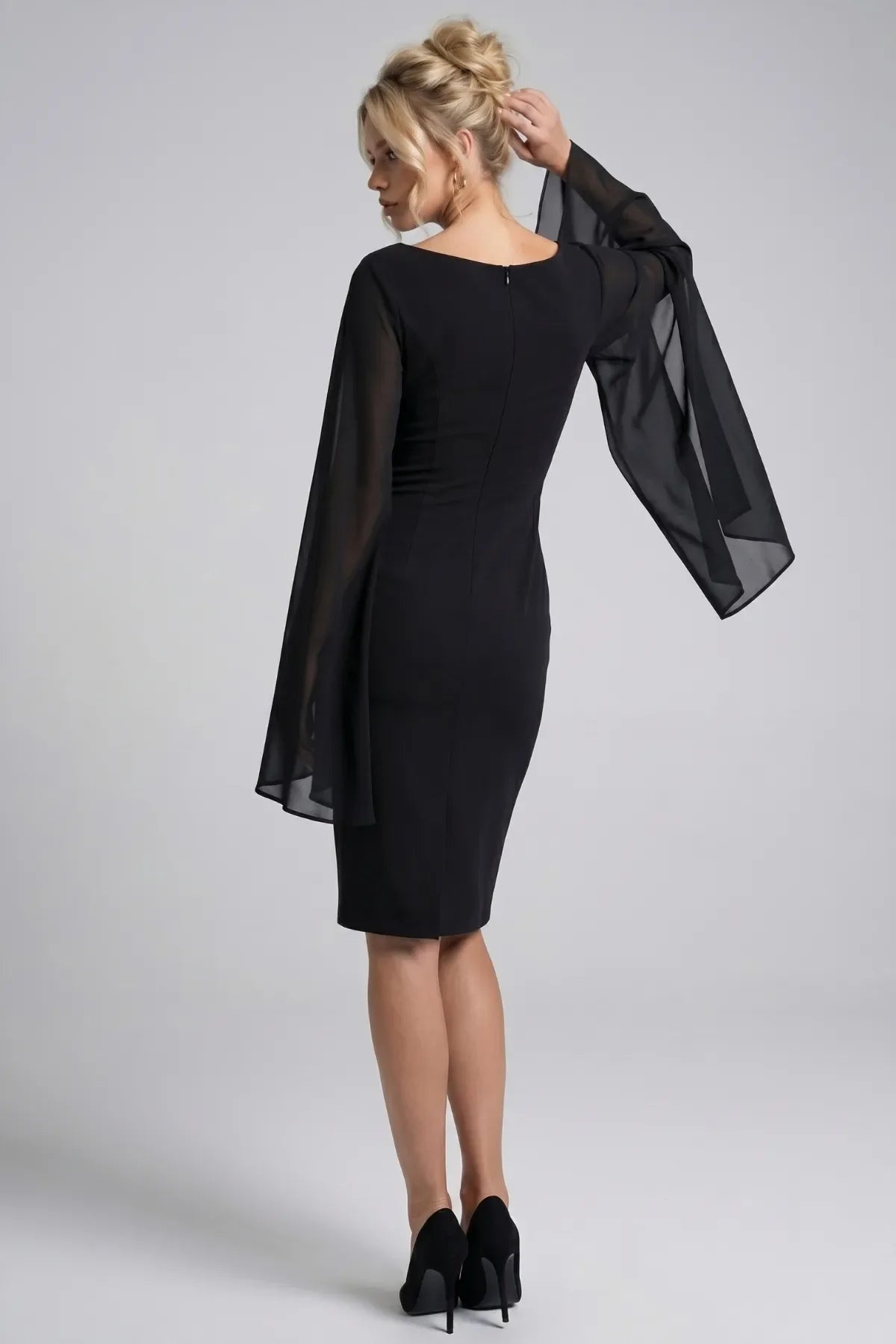 Back of the Rebeka black dress with V back, concealed zipper, hem vent and draping sheer cape sleeves