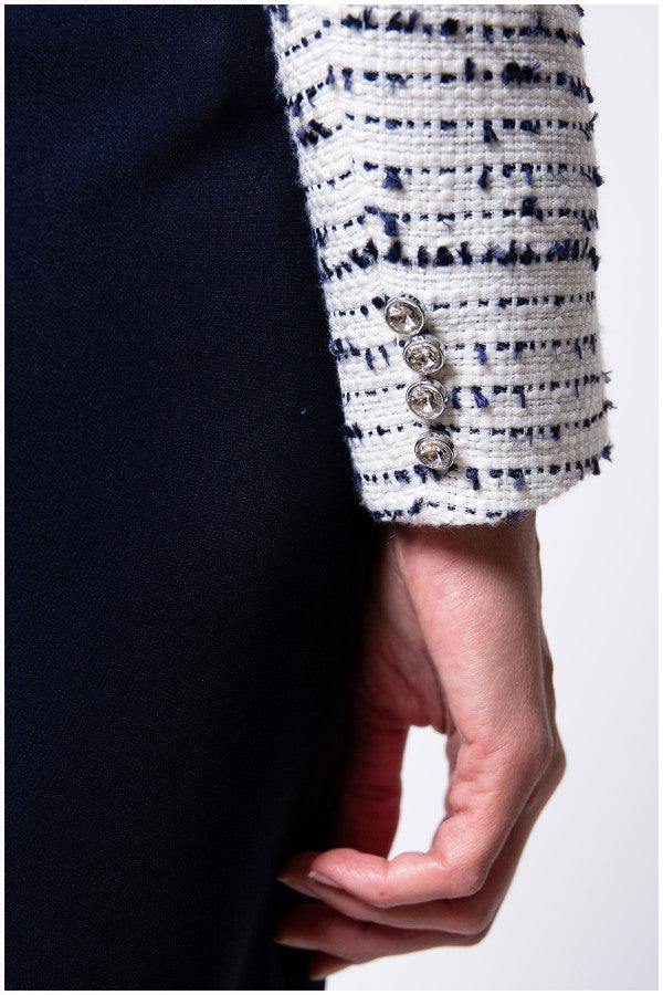 Close up of navy trim and crystal cuff buttons on white tweed blazer