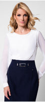 Model in white viscose blouse with sheer sleeves tucked into tweed skirt