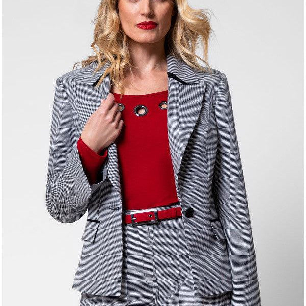 Woman wearing tailored blazer Elena with houndstooth pattern, black collar accents, and matching trousers in a business outfit