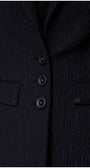 Detail front button view of black textured blazer with vent and subtle texture
