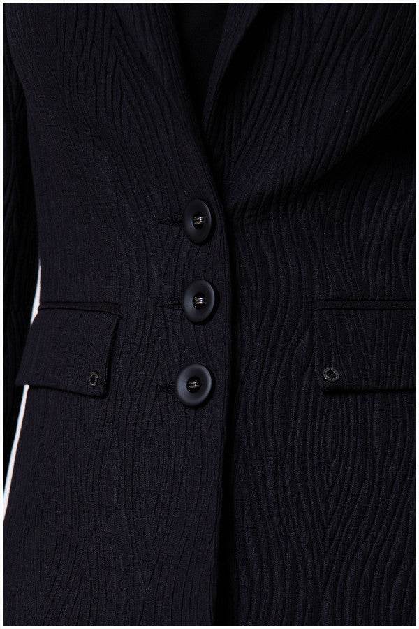 Detail front button view of black textured blazer with vent and subtle texture