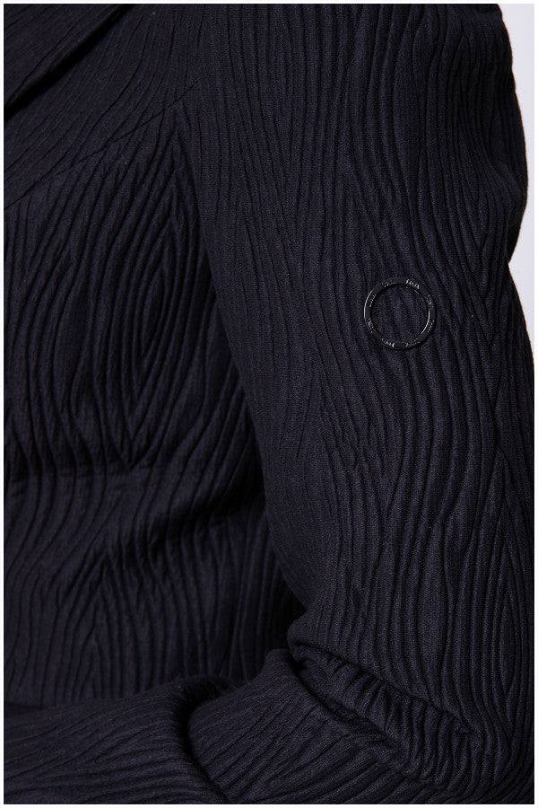 Detail sleeve view of black textured blazer with vent and subtle texture