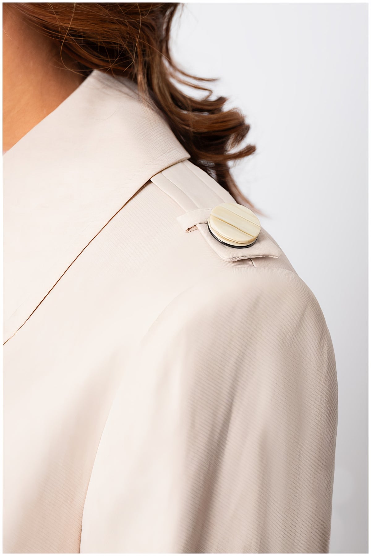 Close-up of the shoulder detail with button on the Kim Classic Long Coat in Beige showcasing refined craftsmanship and elegant design.
