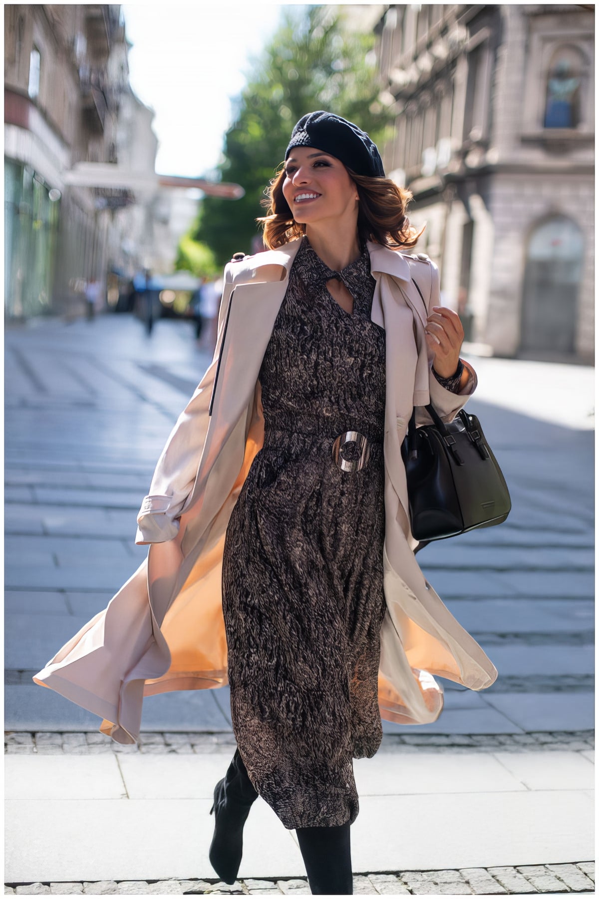 Woman walking confidently on city street wearing Kim Classic Long Coat in Beige over patterned dress and black beret