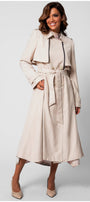 Woman wearing Kim Classic Long Coat in Beige with belt and button details, standing against light background