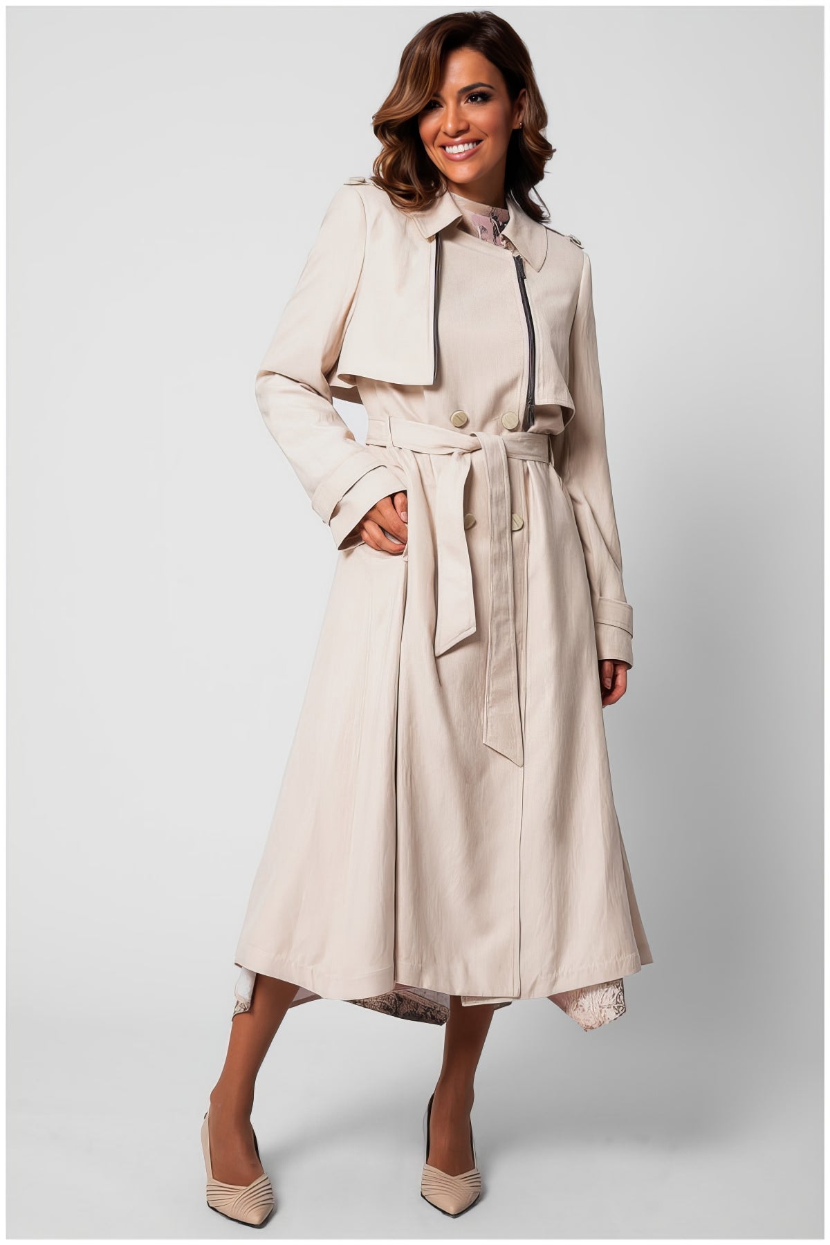 Woman wearing Kim Classic Long Coat in Beige with belt and button details, standing against light background