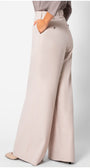 Back view of Natasha Wide Leg Trousers in Sand Beige showing smooth fabric and wide-leg silhouette with hand in pocket.