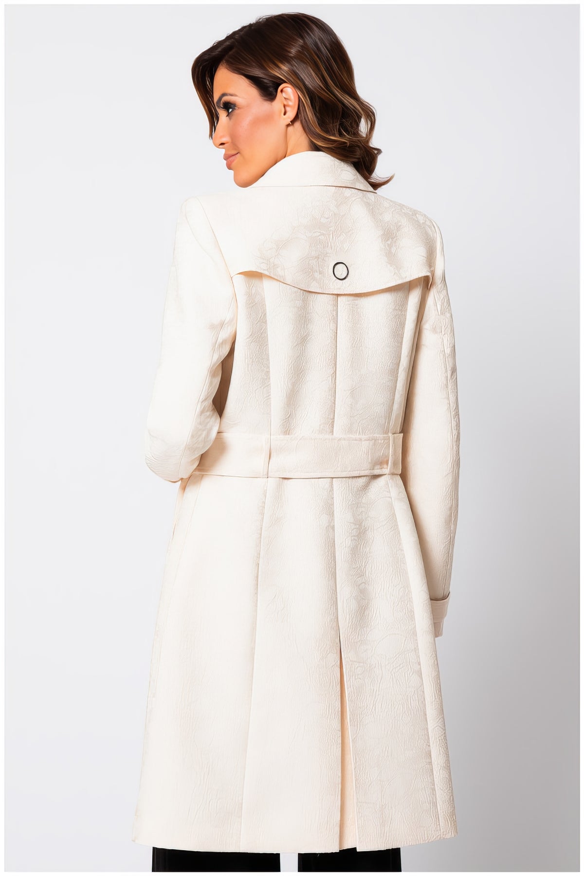 Rear view of a woman wearing the elegant Rea Jacquard Trench Coat in Beige with delicate textured fabric.