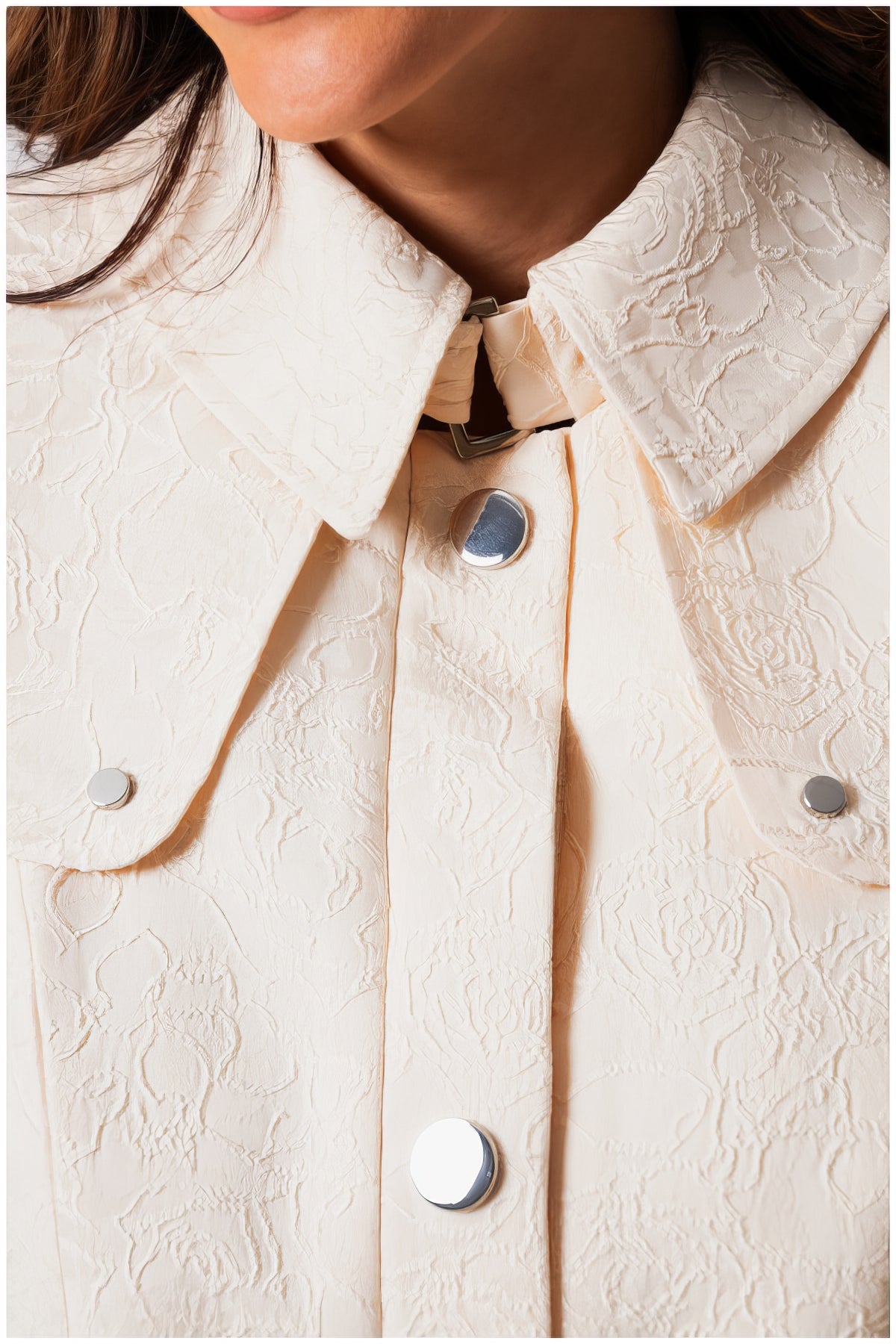 Close-up of textured collar and silver buttons on the Rea Jacquard Trench Coat in Beige showcasing elegant design details
