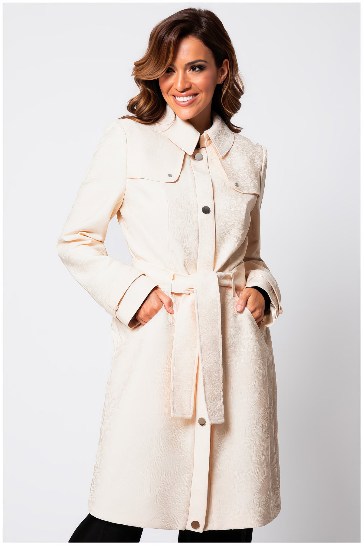 Woman wearing Rea Jacquard Trench Coat in Beige with textured fabric and belted waist posing against white background