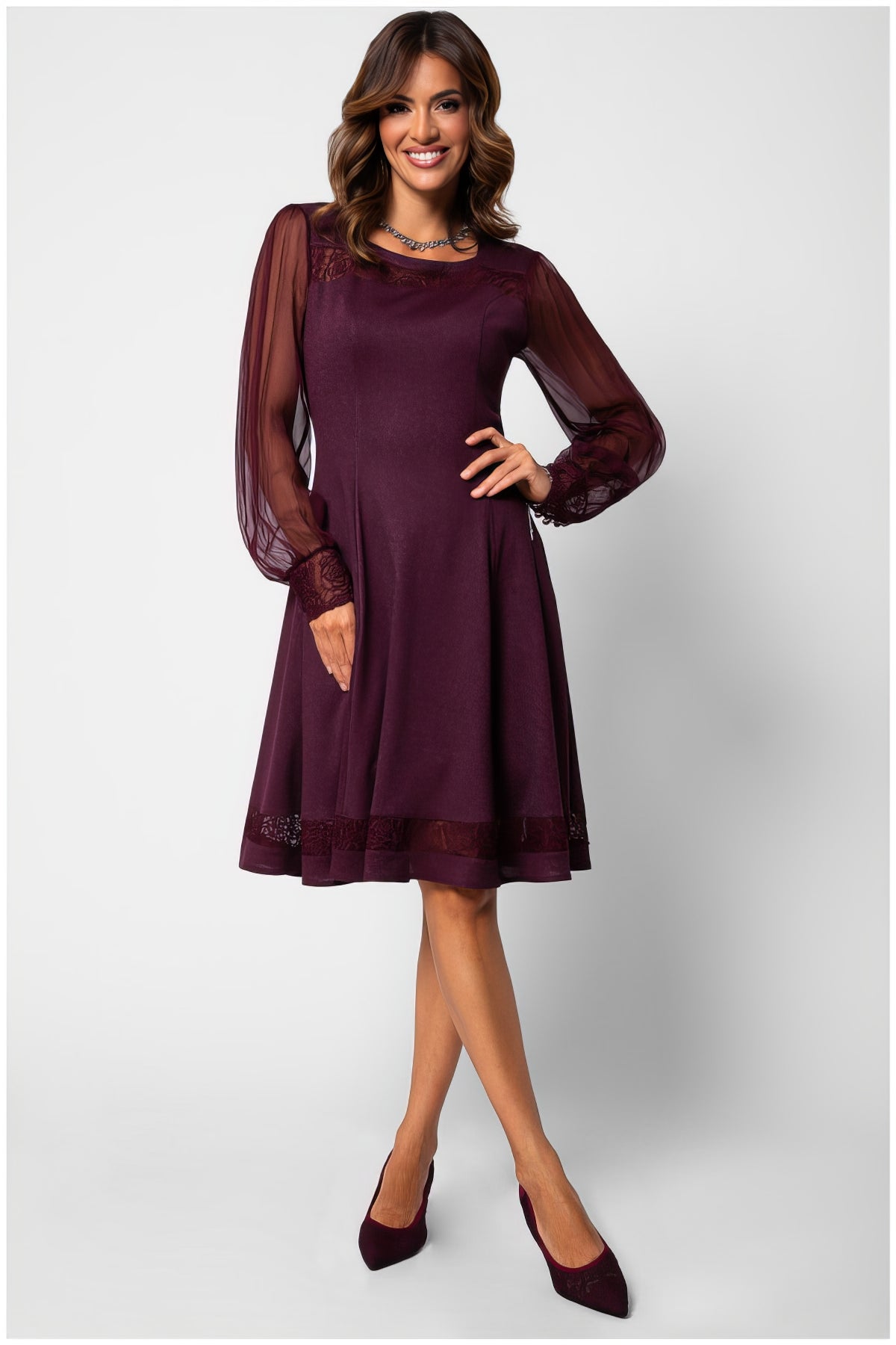 Woman wearing the Jody Lace A-Line Dress in Bordeaux with sheer sleeves and lace details, styled elegantly with matching shoes.
