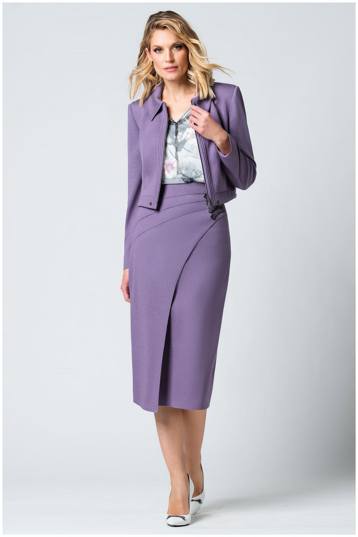 Woman wearing Neda Cropped Zip Blazer in Lilac styled with a matching skirt and white heels on a plain background
