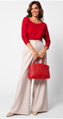 Woman wearing Eva Classic Top in Scarlet Red with beige high-waist wide-leg pants holding a red handbag
