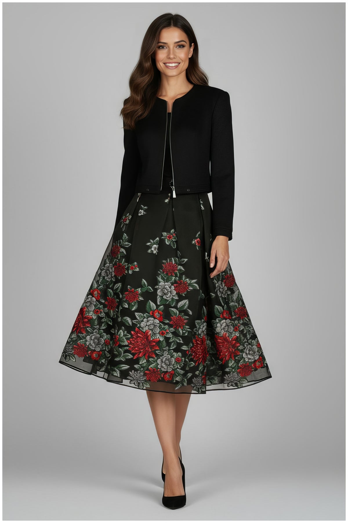 Woman wearing Frida Cropped Zip Blazer in Black styled with floral midi skirt and black heels on gray background