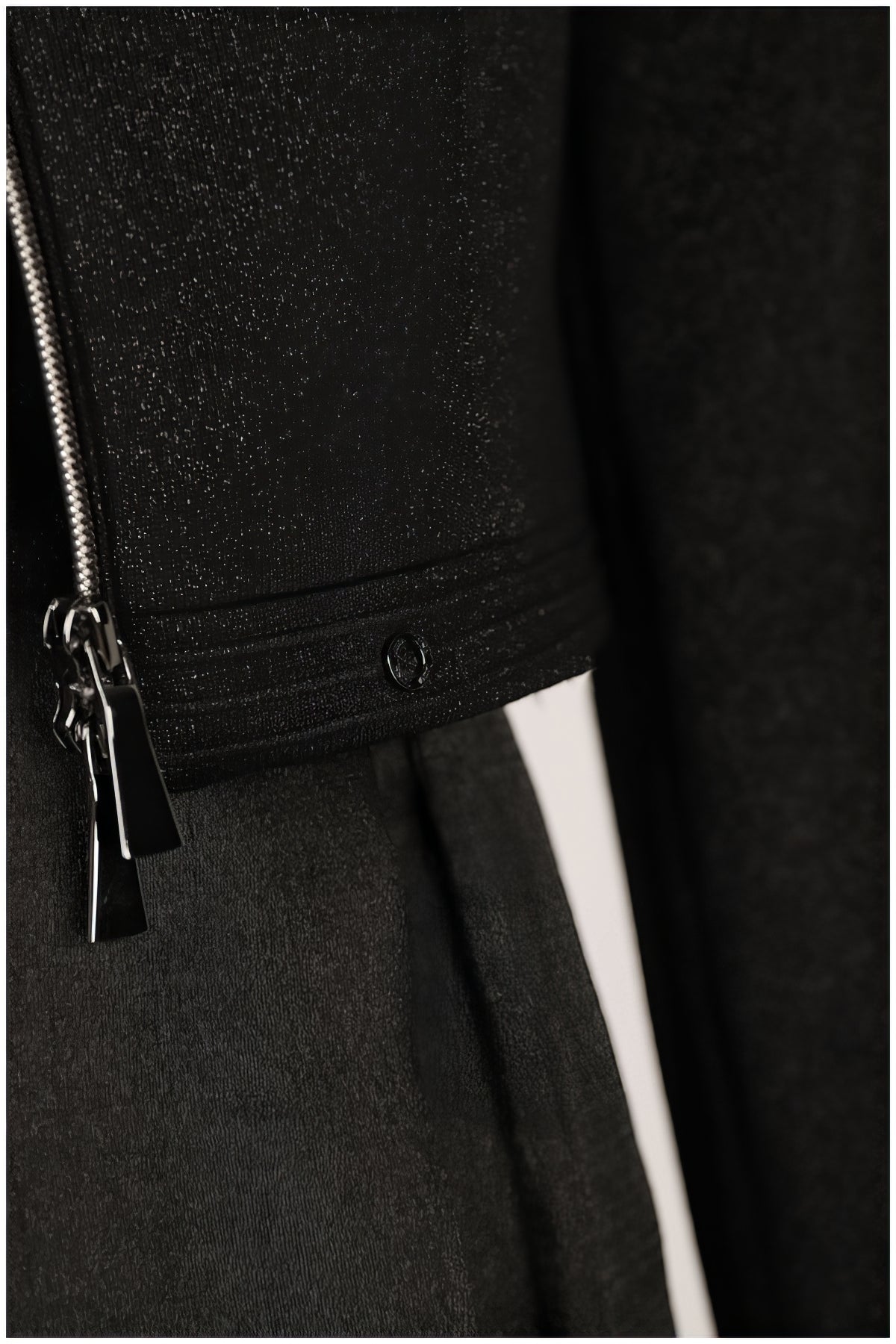 Detail of silver zipper and textured fabric on the Frida Cropped Zip Blazer in Black showing craftsmanship and modern tailoring.