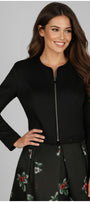 Woman wearing Frida Cropped Zip Blazer in Black with long sleeves and a subtle zip front closure.
